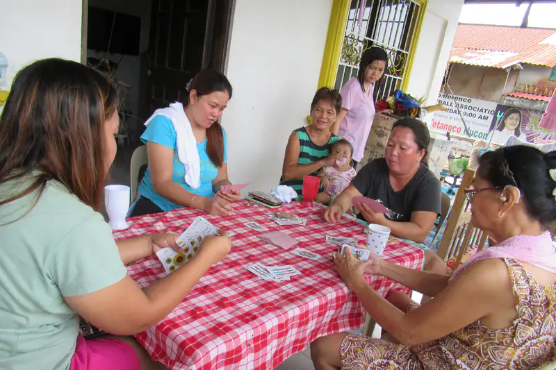 Filipina women playing cards together around a table